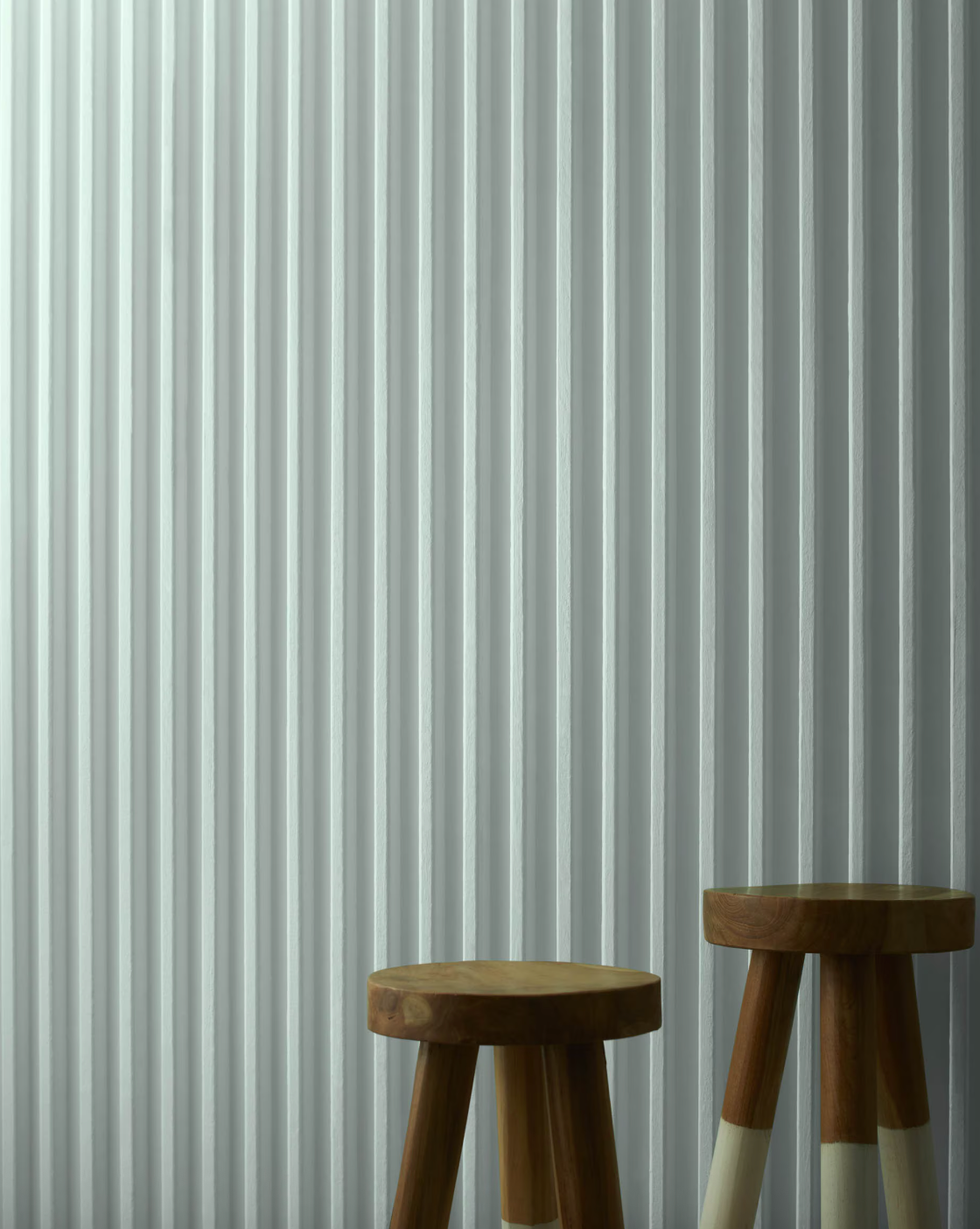 Two wooden stools positioned in front of a vertical striped wall.