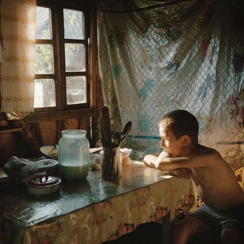 Een jongetje zit te mijmeren in een keuken in Budeti een dorpje in de Roemeense plattelandsregio Maramures