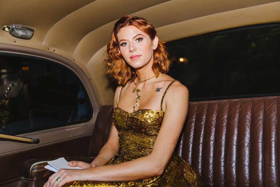 a woman in a gold dress sitting in a car