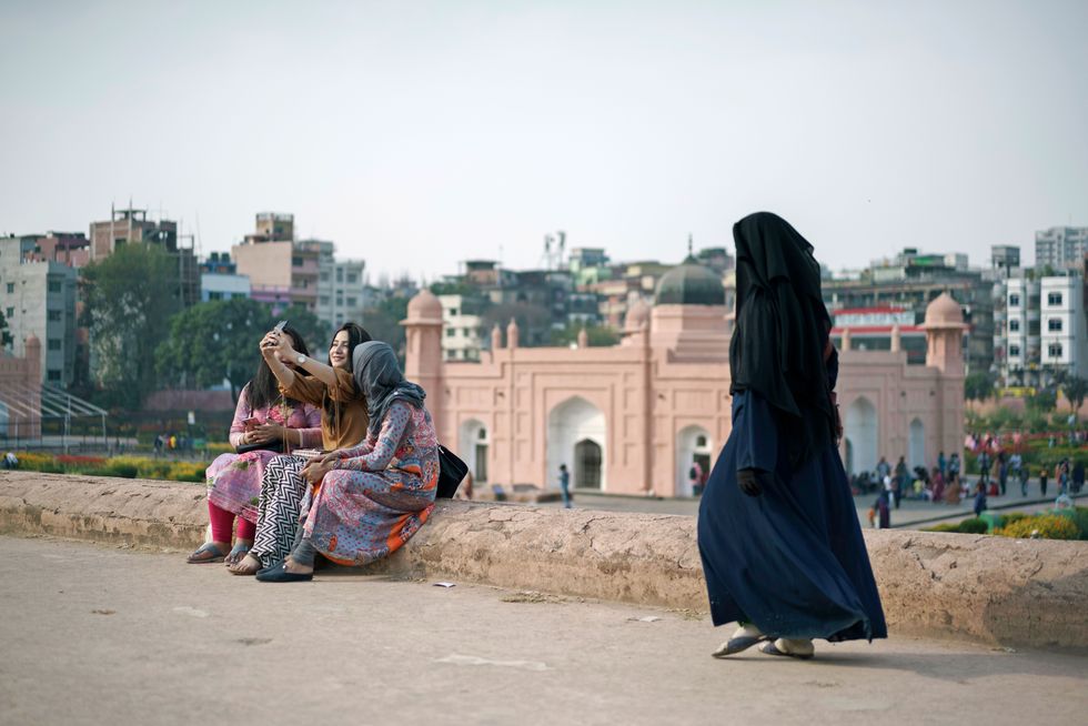 Drie meisjes maken een selfie met op de achtergrond Ahsan Manzil het roze paleis