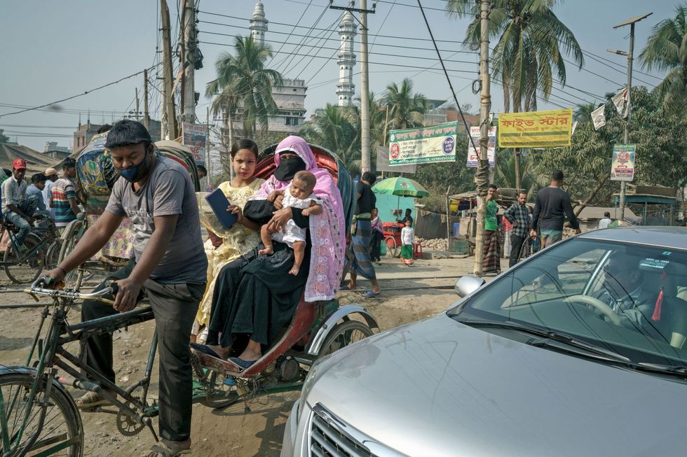 Een vrouw een meisje en een baby achterop een etsriksja aangevoerd door een illegale elektrische motor