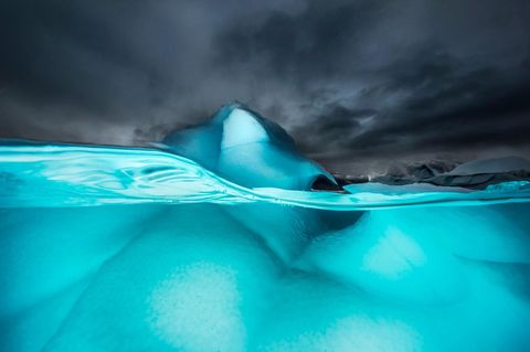 De Scoresbysund aan de oostkust van Groenland is het grootste fjord ter wereld Afkalvende rivieren van gletsjerijs produceren ijsbergen die eenmaal in zee door wind en water tot voortdurend veranderende beeldhouwwerken worden geboetseerd