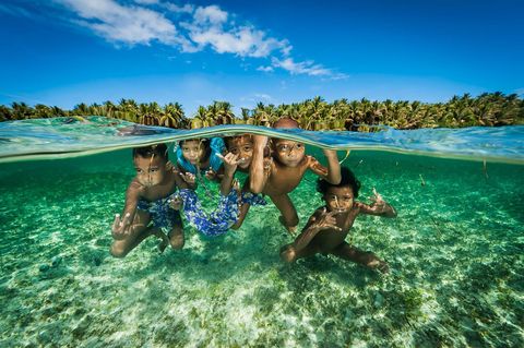 Afstammelingen van de legendarische zeevaarders van het atol Satawal spelen in het warme water voor de kust van de Carolinen in de Federale Staten van Micronesi