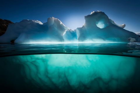 In de buurt van het Rode Eiland in het Groenlandse fjord Scoresbysund glanst een ijsberg in de late middagzon IJsbergen zijn een goede metafoor voor de wereldzeen slechts een fractie ervan is zichtbaar met het blote oog