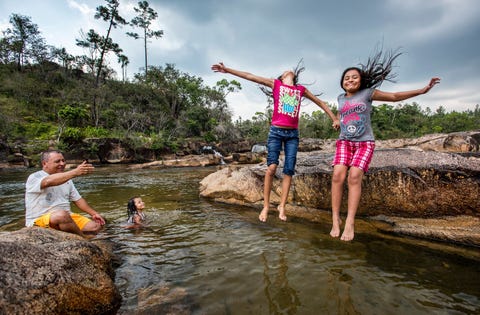 Meisjes springen in het water bij Rio On Pools een onder locals populaire plek voor een gezinsuitje in het Mountain Pine Ridge Forest Reserve