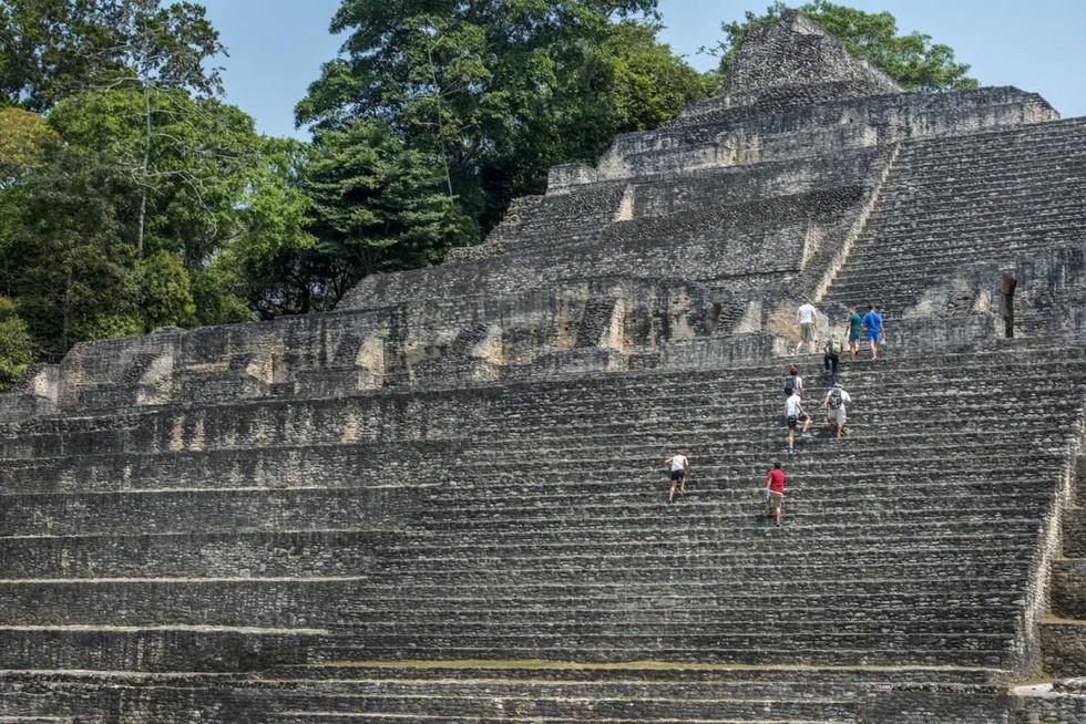 Toeristen beklimmen de trappen van een ruim veertig meter hoog complex van paleizen tempels en woningen in Caracol ooit een Mayametropool in de heuvels van westelijk Belize De Mayas noemden het bouwwerk op de foto heel toepasselijk Caana Hemelse Plek dicht bij de bovenwereld van hun goden