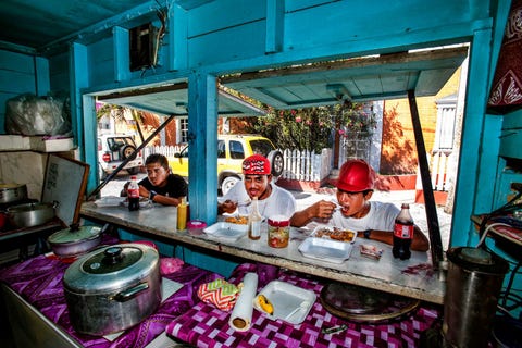 Belizianen lunchen op het heetst van de dag bij een eettentje in San Pedro op het noordelijk gelegen eiland Ambergris Caye door Madonna ooit bezongen als La Isla Bonita Voor de middelste man staat een flesje hot sauce onmisbaar bij de gerechten in Belize Hoe heter hoe beter Beroemd zijn de habanero pepper sauces van Marie Sharps