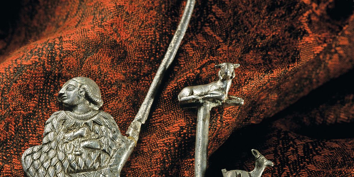 Zilveren spelden met dierlijke en menselijke figuren De vrouw is gekleed in een kaunakes een wollen mantel van Mesopotamische oorsprong met een patroon van schijnbaar overlappende bladeren of veren