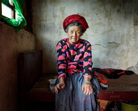Pema Lamu 73 zit in haar slaapkamer in het dorp Zhashi Zoals veel dabu is haar lichaam verweerd door jarenlange harde arbeid op het veld Terwijl mannen bij nog zwaardere klussen meehelpen zijn het de vrouwen die het land bewerken
