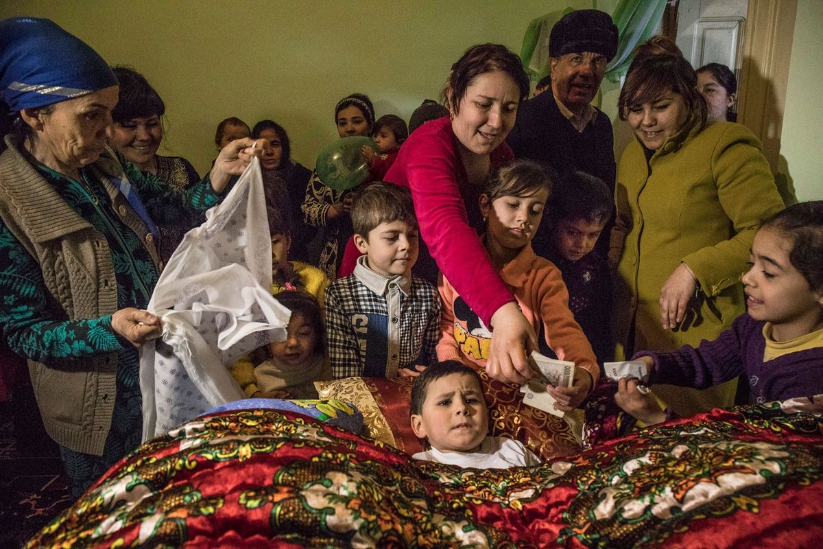 De 5jarige Beknur Bakhtiarov krijgt geld cadeau na zijn besnijdenis in zijn ouderlijk huis in Xiva in Oezbekistan