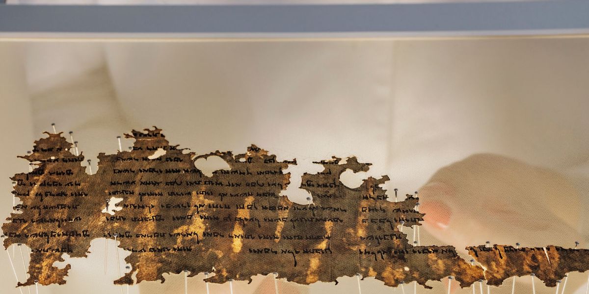Een conservator van de Isralische Oudheidkundige Dienst prepareert een stukje van de Dode Zeerollen zodat het kan worden gexposeerd De snipper papyrus hier op zn kop wordt tussen twee lagen gaas gelegd die worden afgespeldom daarna te worden vastgenaaid