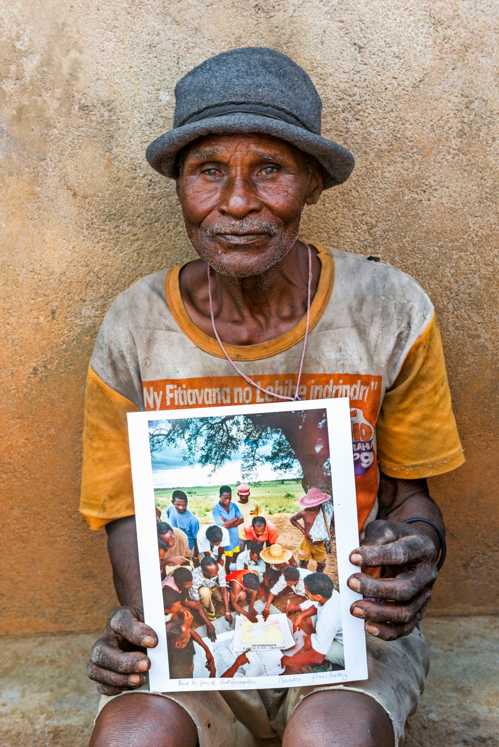 Man met de foto van een dorpsbijeenkomst in 1998 over het vaststellen van de grenzen van het Zombitse Vohibasia Nationaal Park Hij is een van de weinige mannen op de foto die nog in leven zijn 2017