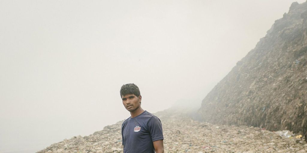 In Bhalswa zoekt recyclingwerker Prem op een reusachtige vuilnisbelt naar metaal de vuilnisbelt brandt permanent en braakt giftige rook uit