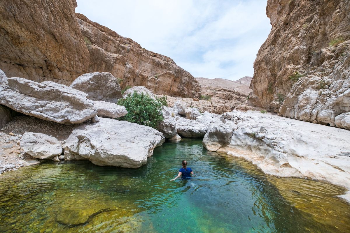Zwemmen in het heldere water van Wadi Bani Khalid Vrouwen dienen in Oman een tshirt en broek boven hun zwemkleding te dragen