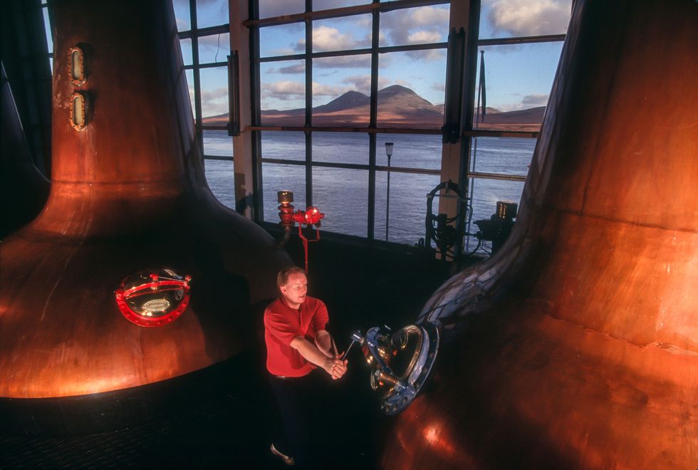 Alan McGhee werkt bij distilleerderij Caol Ila op het eiland Islay met in de verte de Paps of Jura de beroemde bergen van het eiland Jura