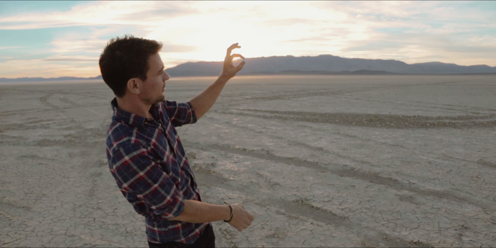WYLIE OVERSTREET HOLDING A MARBLE IN HIS HAND AGAINST THE SKY