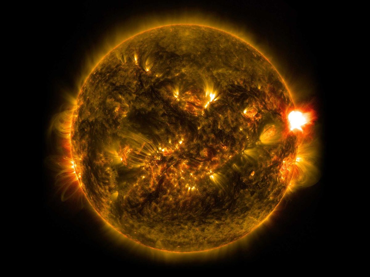 Een zonnevlam van klasse M barst aan de rechterzijde van de zon uit in een opname die op 12 januari 2015 kort vr middernacht EST werd gemaakt In deze opname van het Solar Dynamics Observatory van de NASA is het licht van twee golflengten gecombineerd van 171 en 304 ngstrm