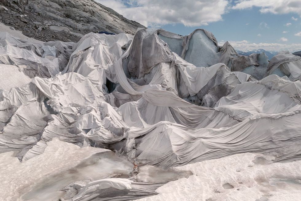 Het uiteinde van de Rhnegletsjer in Zwitserland is bedekt met een kunststof doek Een in het ijs uitgehouwen grot trekt hier al sinds 1870 toeristen aan Het vijftig hectare grote doek blijft het hele jaar liggen en voorkomt dat de grot verder smelt