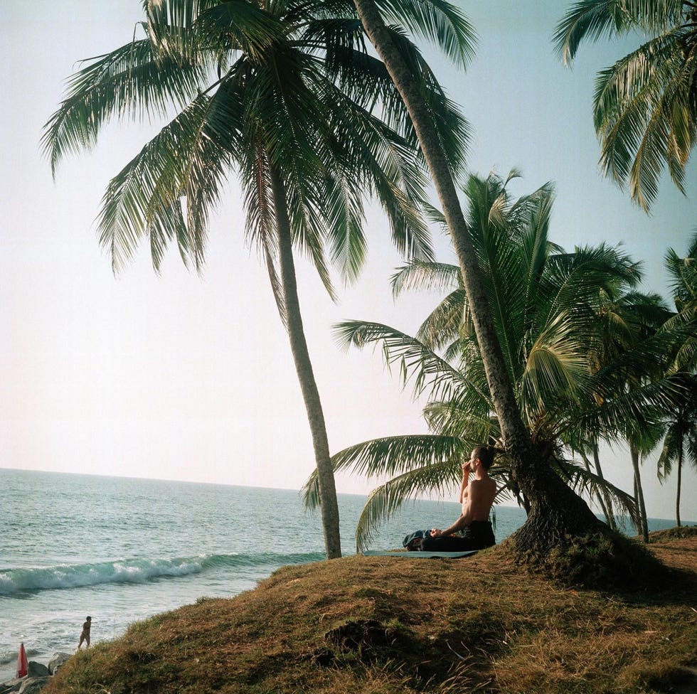Een yogi mediteert met uitzicht op zee op Black Beach in de Indiase staat Kerala