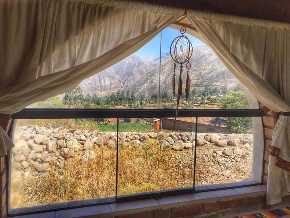 Het raam van het retreat center Pachamama Wasi dat wordt gerund door een familie biedt een panoramisch uitzicht over de Valle Sagrado de los Incas