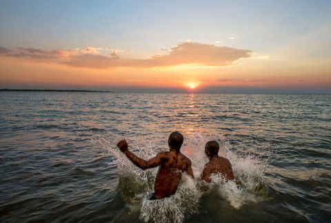 Twee medewerkers van de Pumulani Lodge zoeken tegen zonsondergang verkoeling in het zuidelijke deel van het Malawimeer