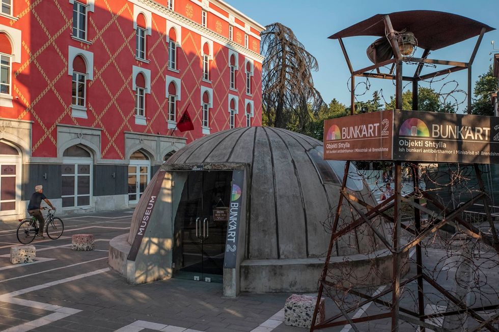 In het centrum van Tirana leidt de koepelvormige ingang van BunkArt 2 naar een atoomschuilkelder uit de tijd van het communisme Het ondergrondse bouwwerk is omgetoverd tot een museum voor geschiedenis en kunst De ingang is ontworpen als een van de tienduizenden tweepersoonsbunkers die onder het Hoxharegime in heel Albani werden gebouwd