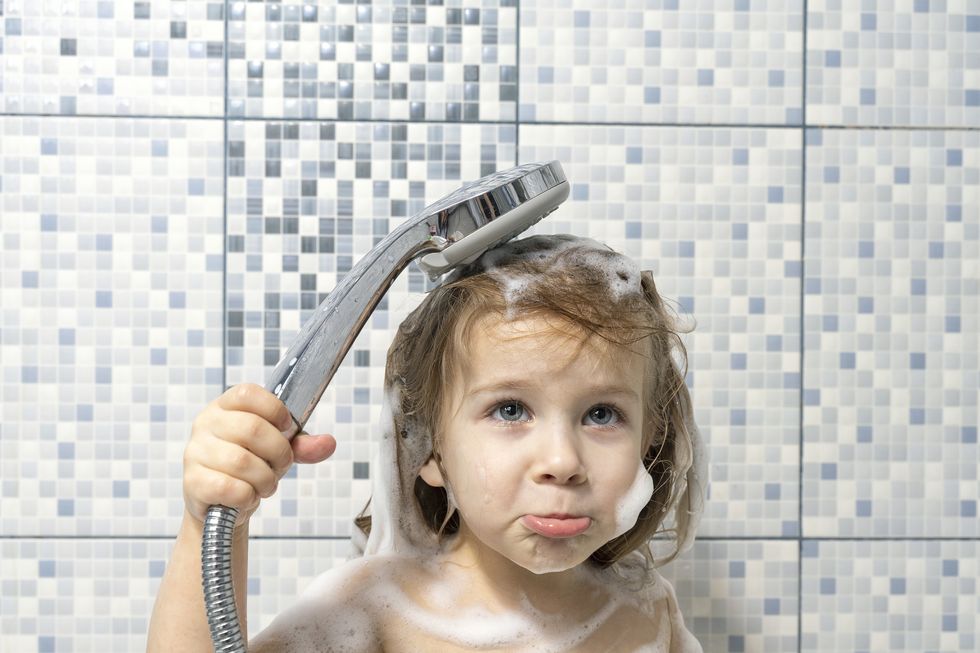 a child of 4 years old is covered with foam in the bathtub in his hand holding a shower, there is no water, the baby is upset the child can not wash off the soap, water pipe breakage