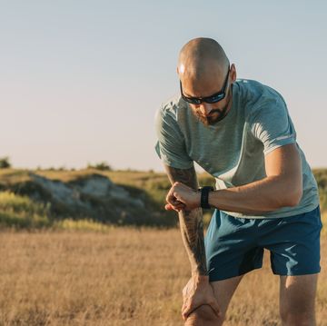 determined to win: a cool man with sports sunglasses taking pulse on his smartwatch