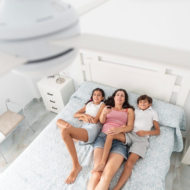 a family uses the remote to activate the electric ceiling fan, view from above a family uses the remote to activate the electric ceiling fan, view from above