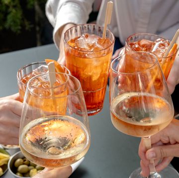 a group of young women drinking spritz, prosecco and white wine cocktails with olives, nuts and chips during aperitif happy hour