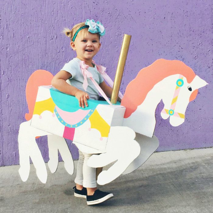 little girl with a box shaped and painted to look like a carousel horse around her