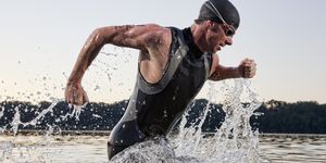 a male triathlete running out of the water