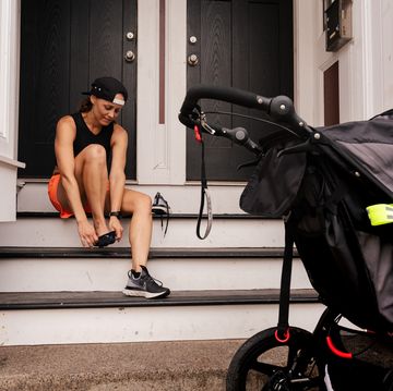 running latest postpartum woman sits on steps and puts her running latest shoes on while a stroller sits on the sidewalk