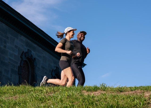 two individuals jogging outdoors on a grassy slope