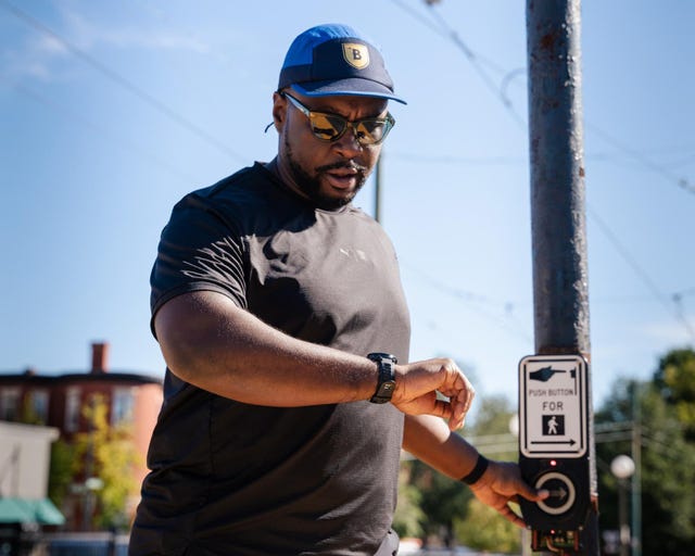 individual pressing a pedestrian signal button at a crosswalk