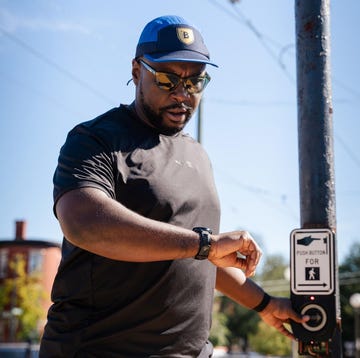 individual pressing a pedestrian signal button at a crosswalk individual pressing a pedestrian signal button at a crosswalk
