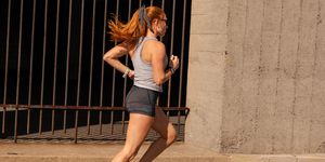 woman running past a cement wall