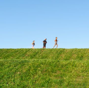 three people running along a ridge with a blue sky