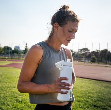 now symptoms runner holds a water bottle after a track workout