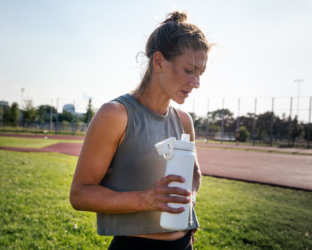dehydration symptoms runner holds a water bottle after a track workout