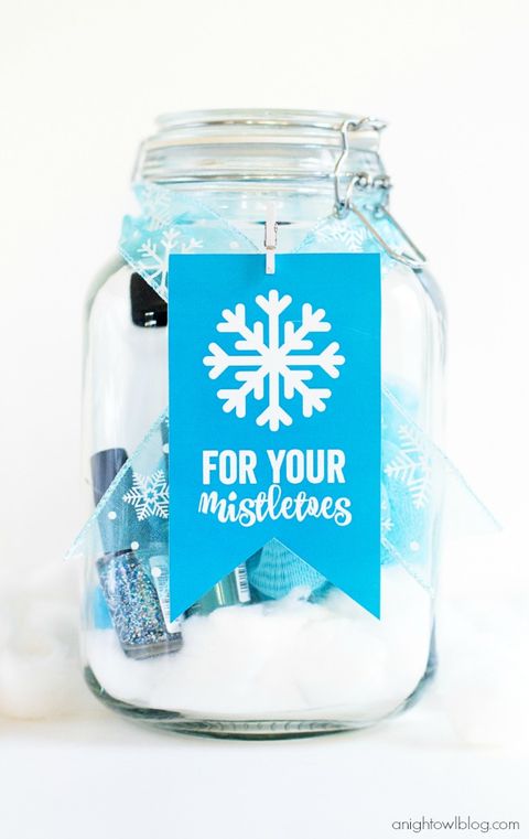 a glass jar with a blue ribbon and blue tag on it reading for your mistletoes inside the jar there are two bottles of nail polish, cotton balls and a blue mesh bath sponge