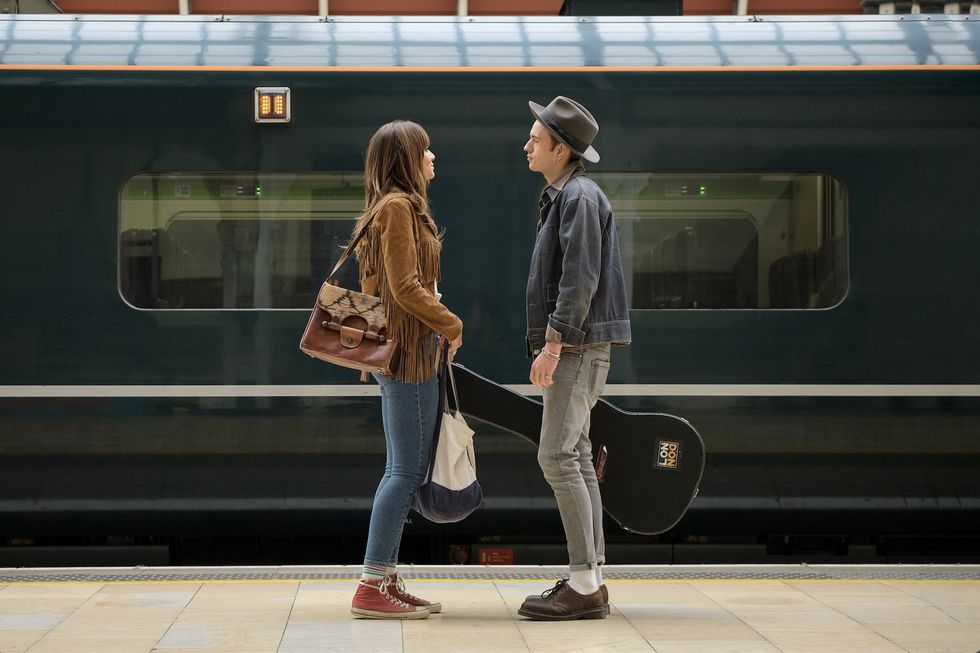 a man and woman standing on a platform in front of a train
