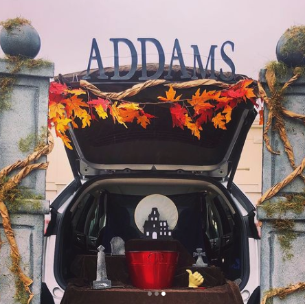 a car decked out for trunk or treat in a addams family theme with a cutout of the family household