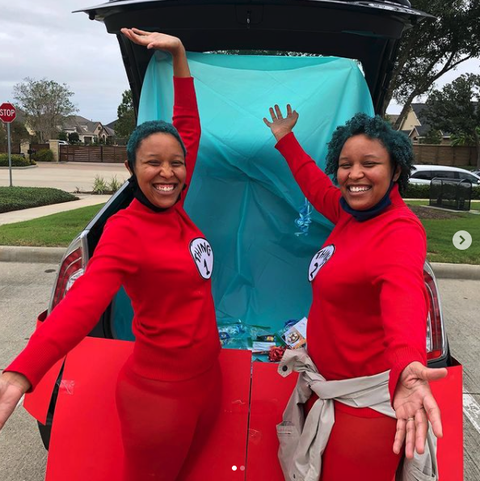 a car decked out for trunk or treat in a cat in the hat theme with people dressed as thing 1 and thing 2 in front