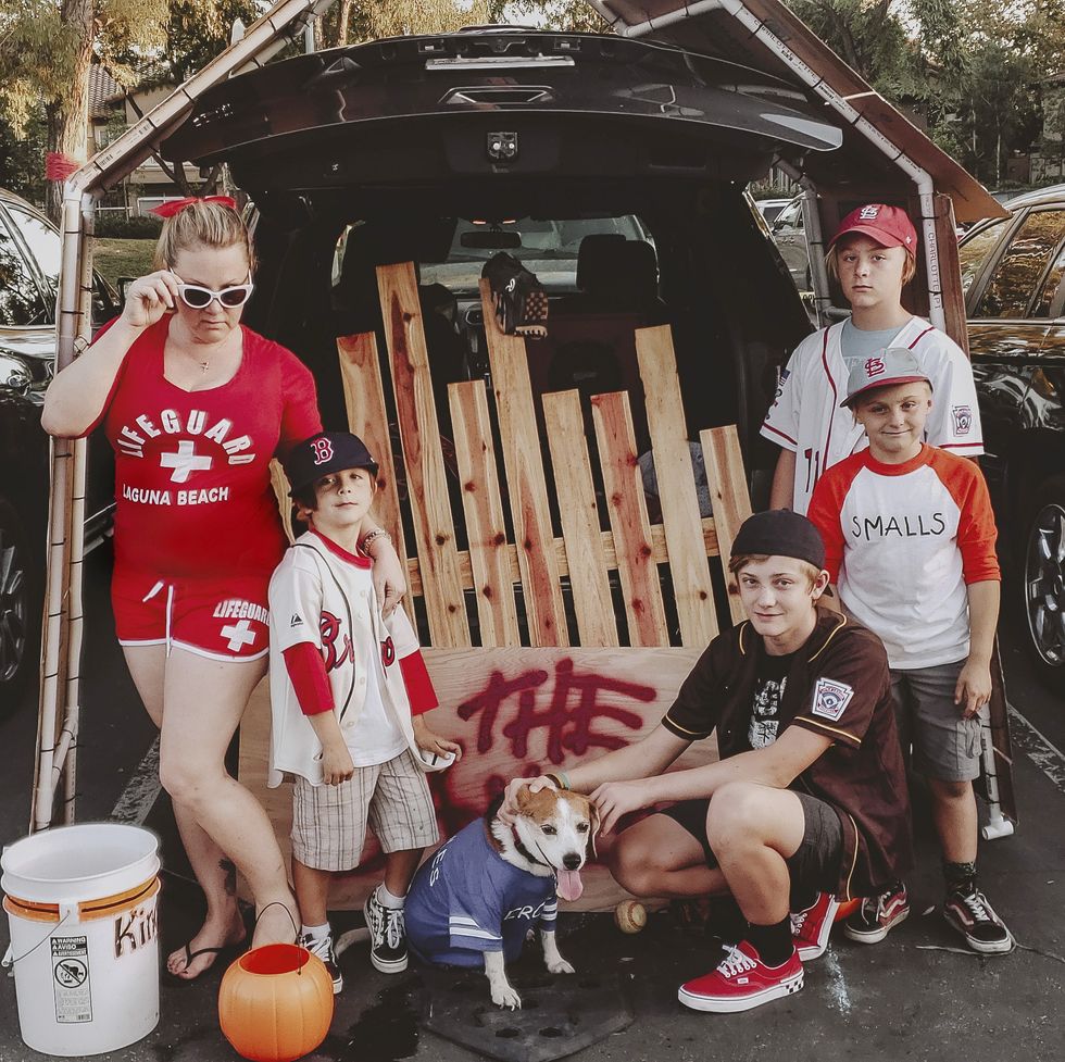 a car decked out for trunk or treat in a sandlot theme with a fake wooden fence and a family dressed like baseball players