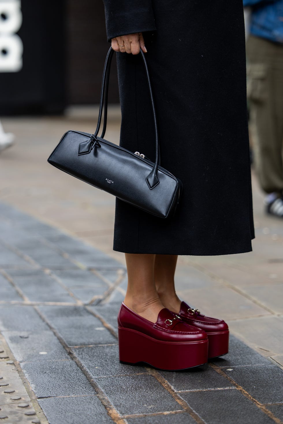 a woman carrying the alaia le teckel bag