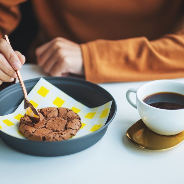 a woman eating delicious chocolate cookie with hot coffee