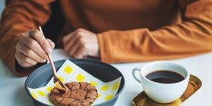 a woman eating delicious chocolate cookie with hot coffee