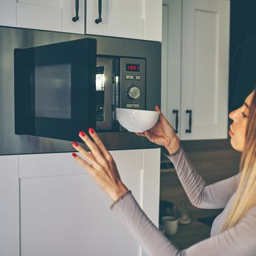 mujer poniendo comida en el microondas