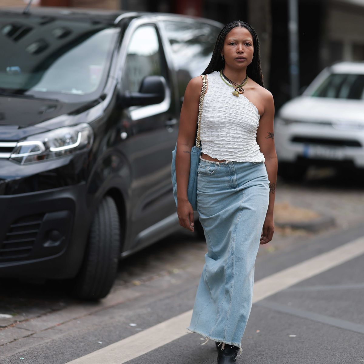 a person walking in a parking lota woman wearing a denim maxi skirt